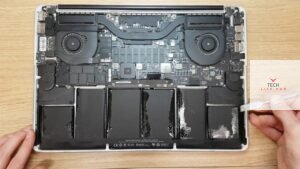 An image of a MacBook Pro 2015 with the back cover removed, revealing the interior components and a new battery ready for replacement